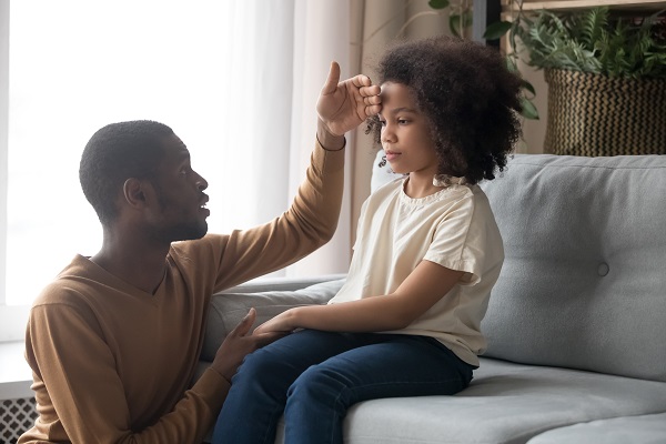 Dad resting his hand on his childs head to check temperature